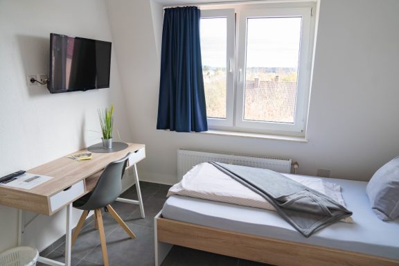 Einzelzimmer mit Bett und Fenster im Hotel Schenk